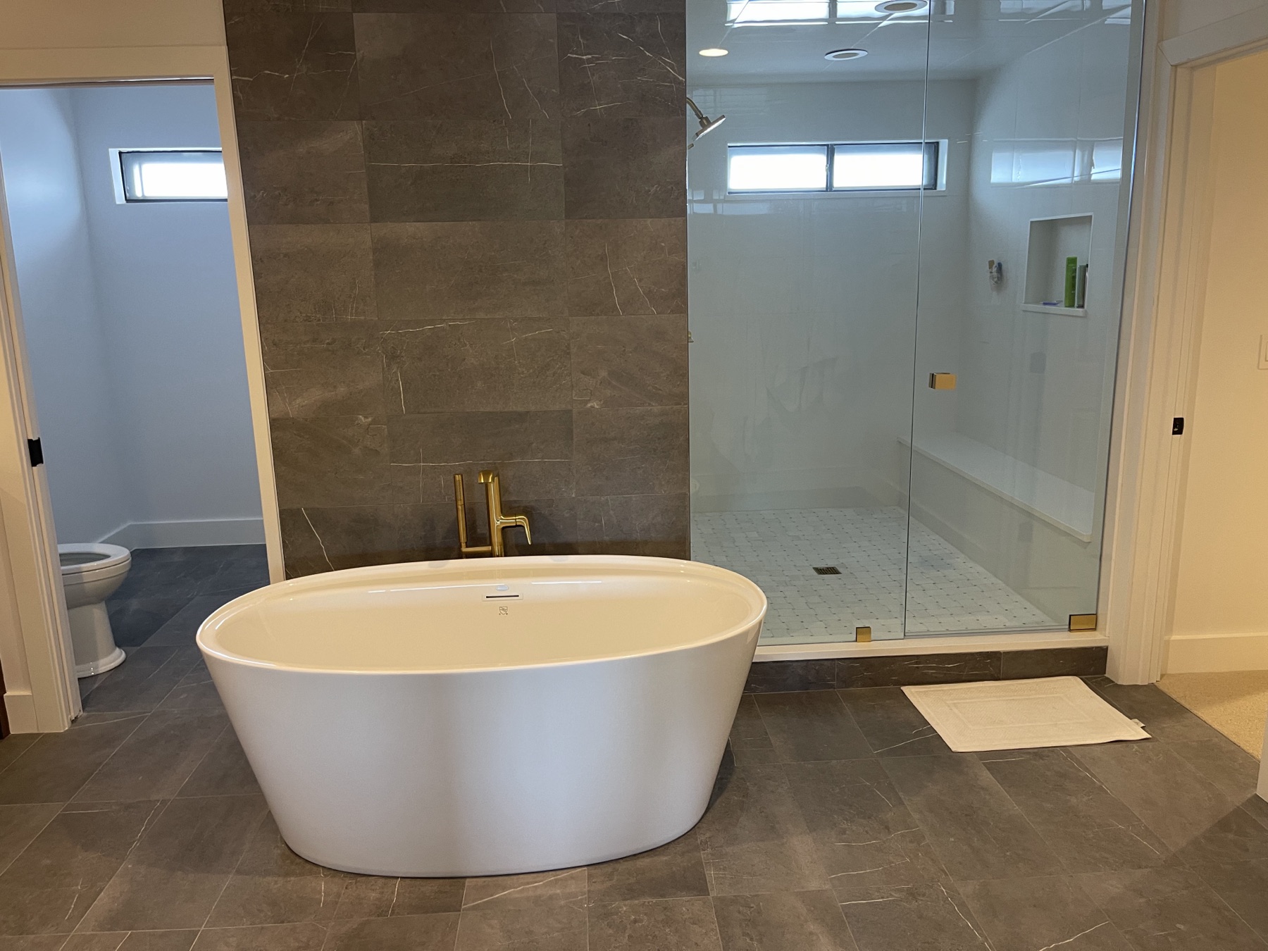 Primary bath with freestanding tub and curbless glass shower